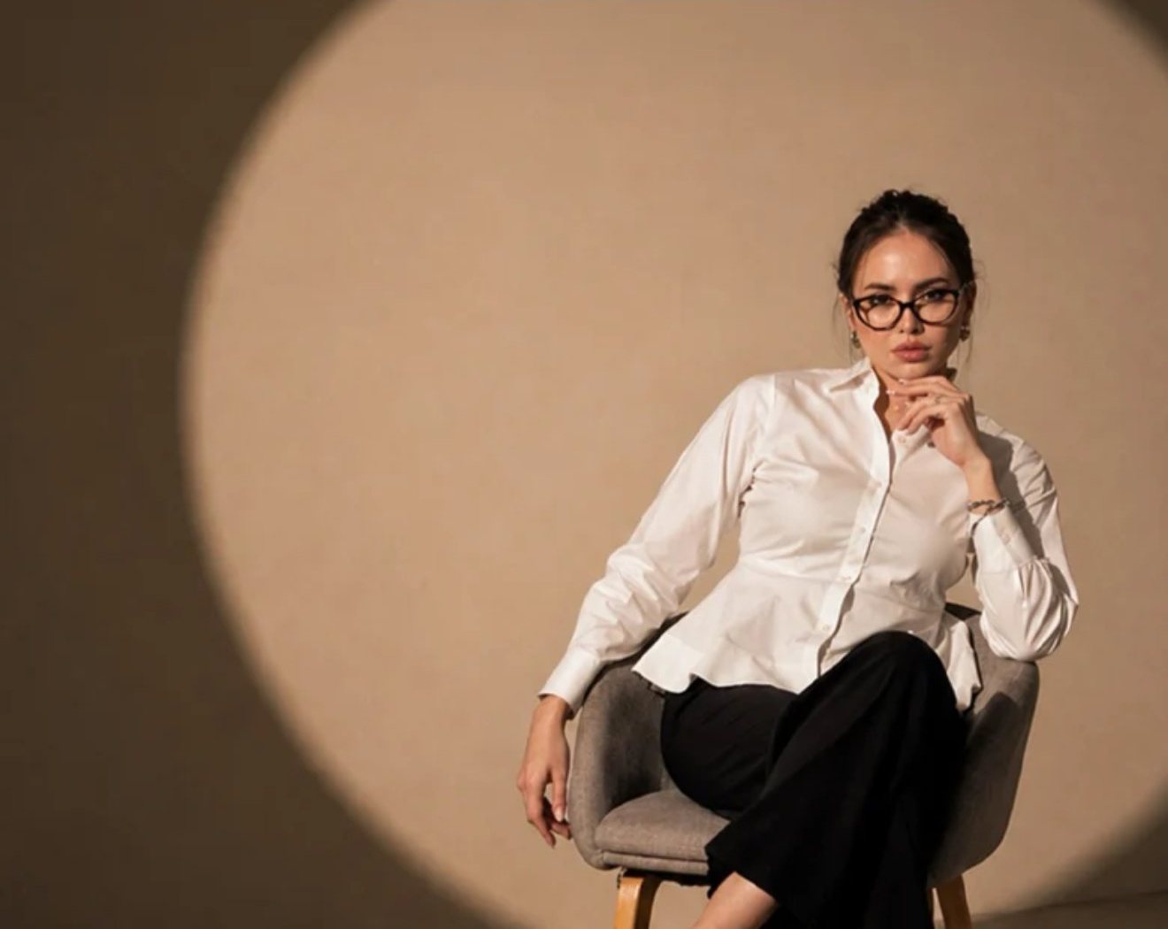 Woman in a white fitted shirt and black trousers, seated