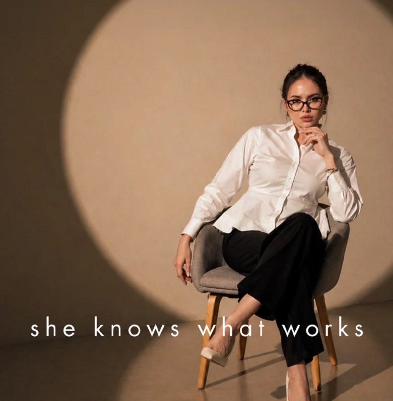 Woman in a white fitted shirt and black trousers, seated